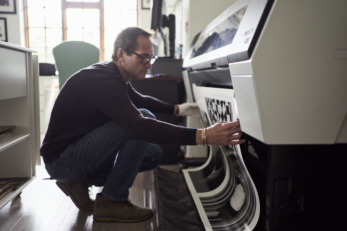 Vincent crouched at the Epson SureColor P9000 as a wide black and white print feeds out of the machine